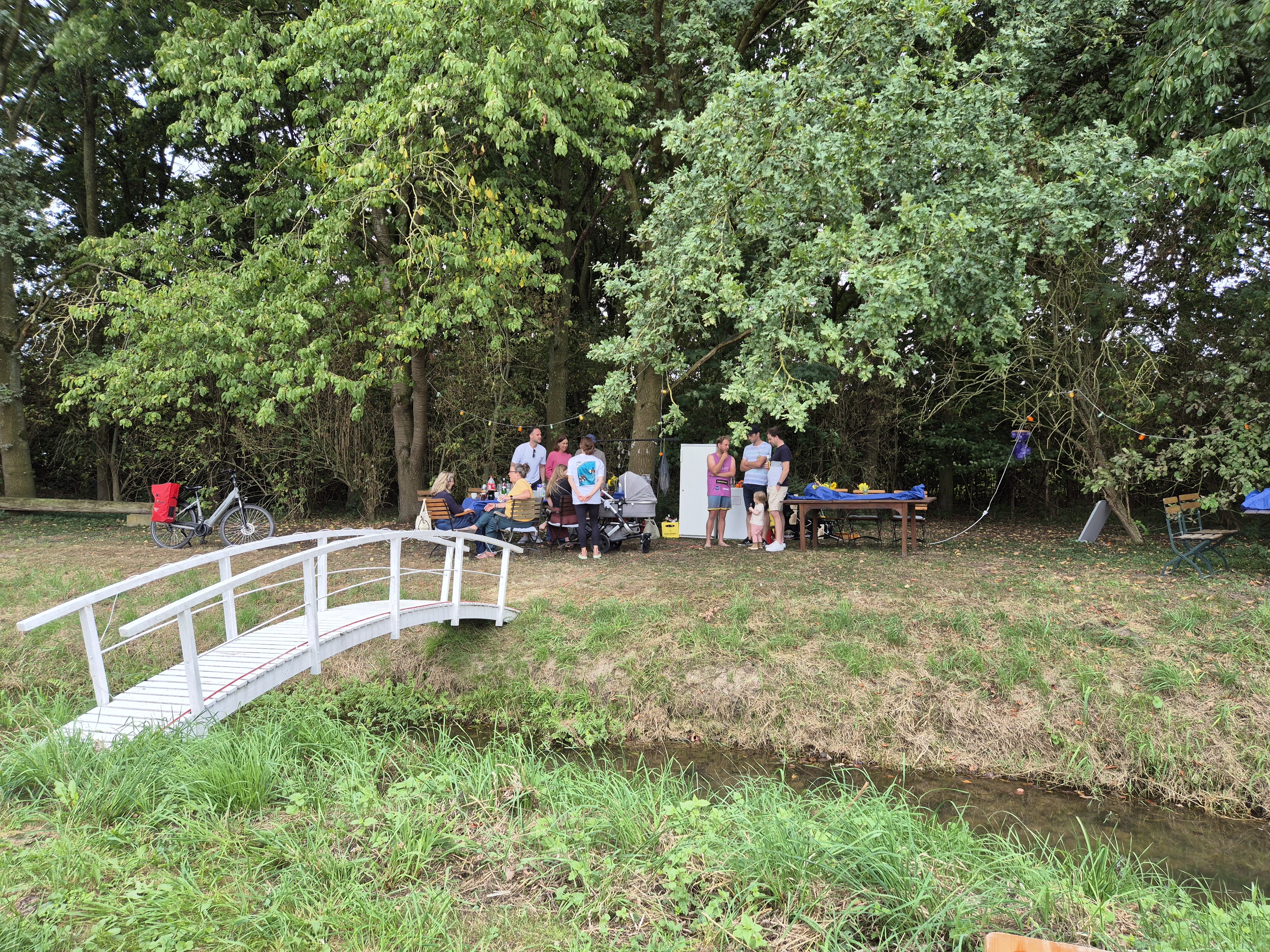 Weiße Brücke und Gäste am grünen Hofrand